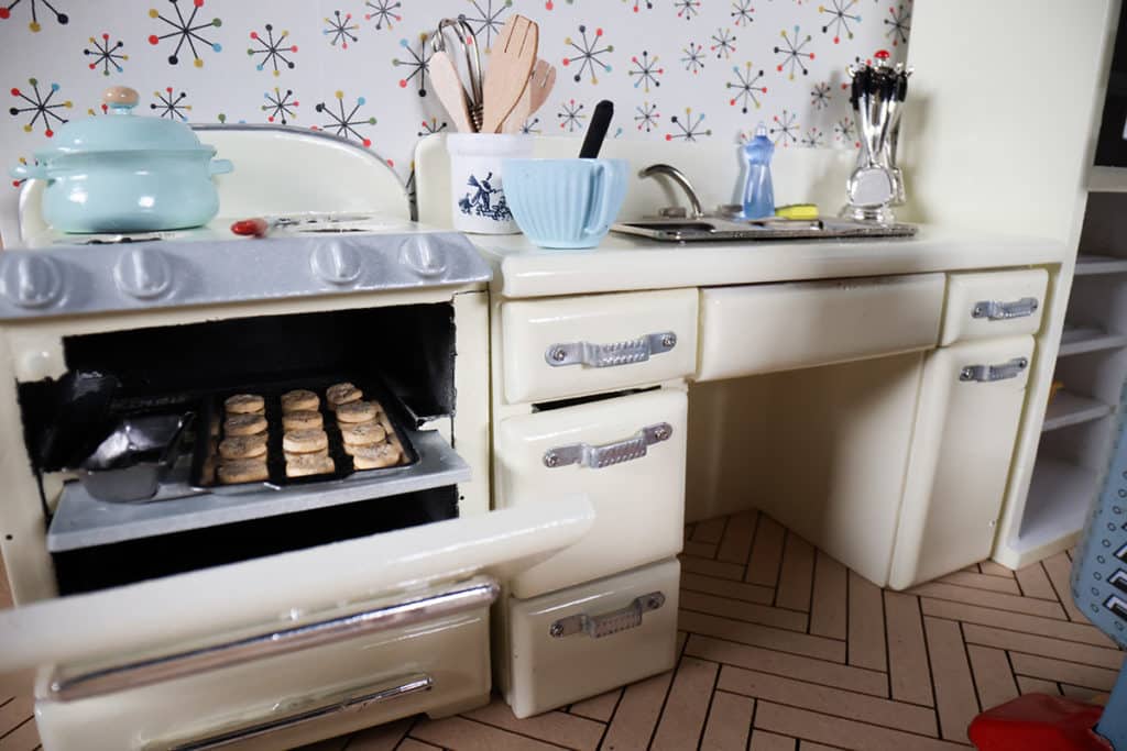 Miniature mid-century modern kitchen with cookies baking in the oven.